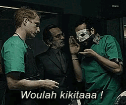 a man with a mask on his face says " woulah kikitaaa " while standing next to two other men