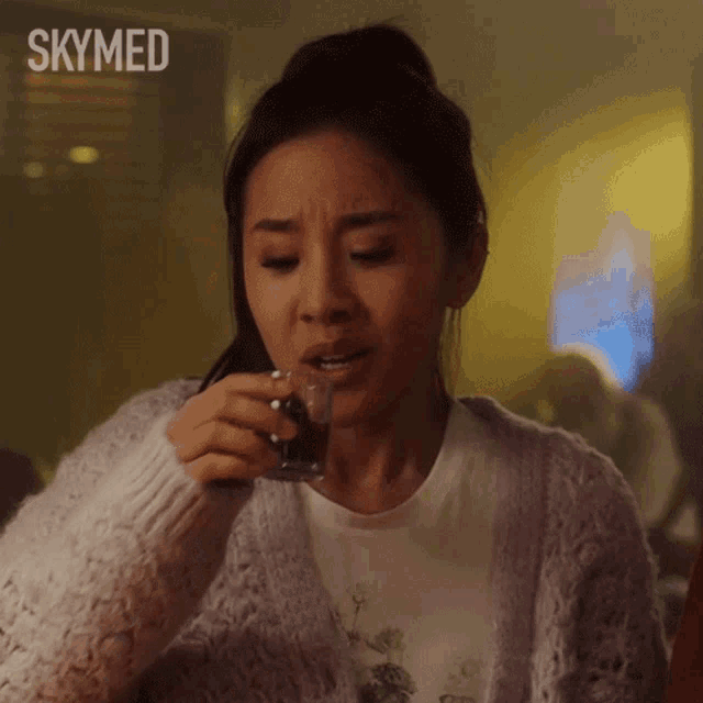 a woman drinking from a glass with the word skymed on the bottom