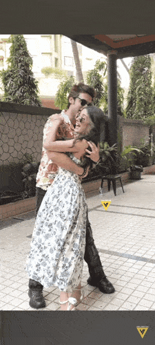 a man in a floral shirt is hugging a woman in a floral dress