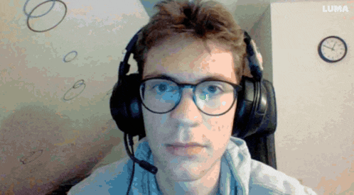a man wearing glasses and headphones is sitting in front of a luma clock