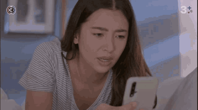 a woman in a striped shirt is looking at her phone with the number 3 on the screen