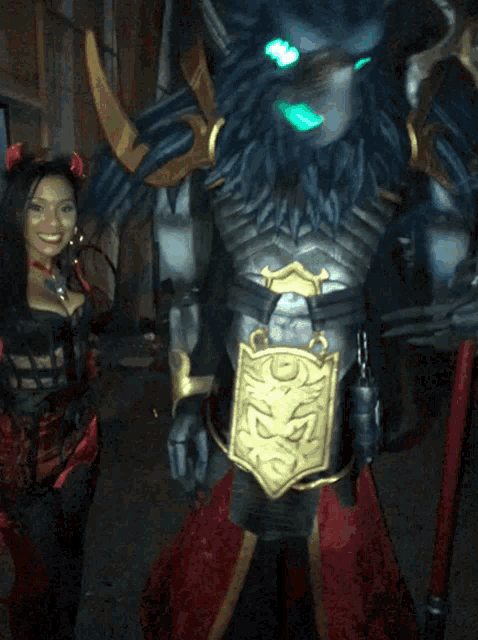 a woman in a red devil costume stands next to a monster in armor