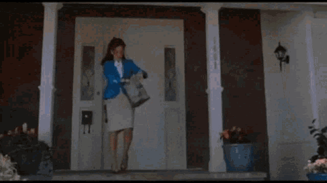 a woman in a blue jacket is standing in front of a white door .