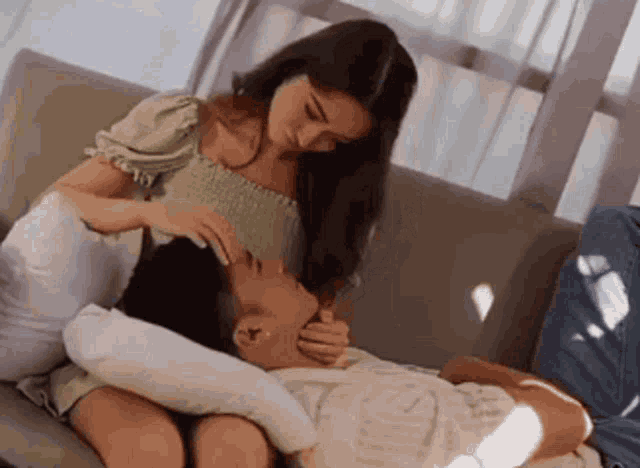 a woman is sitting on a couch with a man laying on her lap .