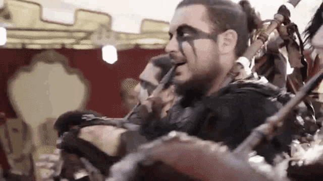 a man with a beard and face paint is playing a musical instrument in a band .