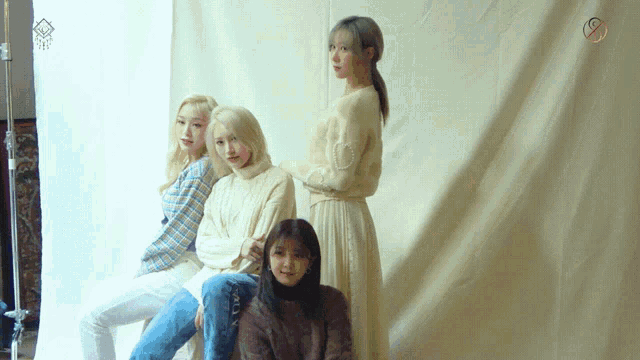 a group of women standing in front of a white cloth with a circle on it