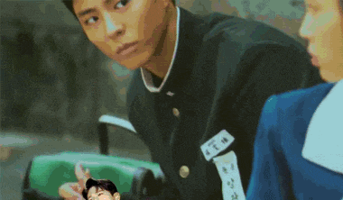 a boy in a school uniform is looking at another boy in a blue uniform .