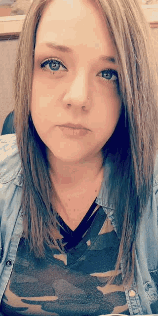 a woman wearing a denim shirt and a camo shirt