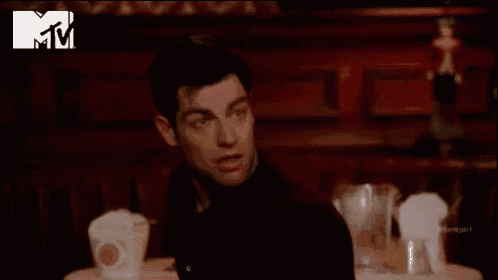 a man is sitting at a table with his arms in the air and a mtv logo behind him