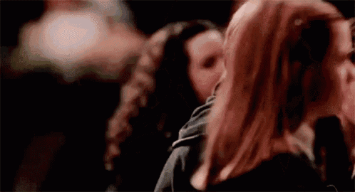 a group of women are standing next to each other in a dark room and kissing .