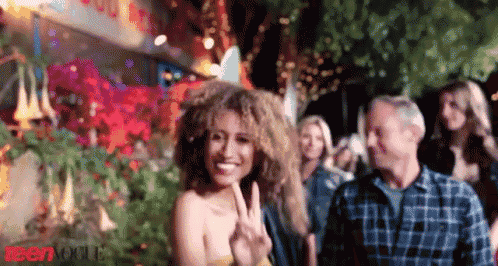 a woman giving a peace sign in front of a crowd of people