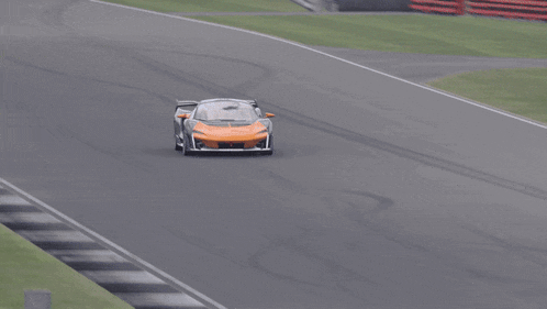 a black and orange sports car is driving down a race track
