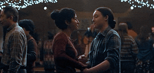 a couple of women are dancing together in a room with a lot of lights hanging from the ceiling .