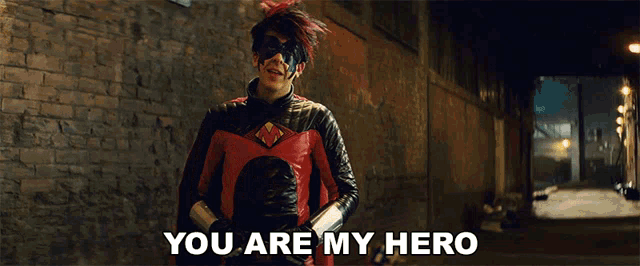 a man in a superhero costume says " you are my hero " in front of a brick wall