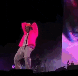 a man in a pink jacket and hat is standing on a stage .