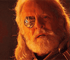 a man with long hair and a beard has a sticker on his eye
