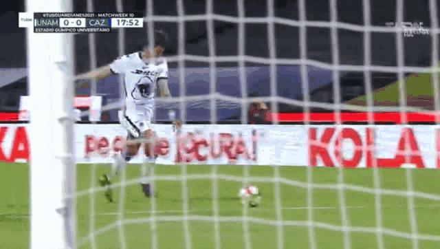 a soccer player is kicking a ball in front of a sign that says kola