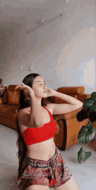 a woman in a red top and shorts is sitting on the floor in front of a couch .