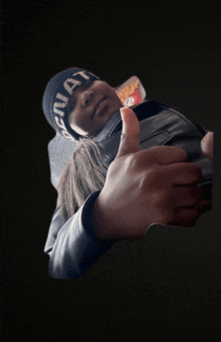 a man wearing a black beanie that says ' original ' on it gives a thumbs up