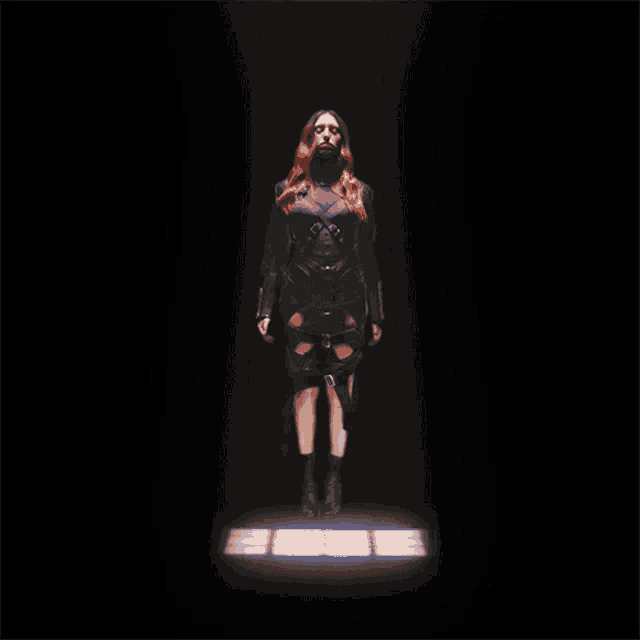 a woman with red hair and a black outfit is standing in the dark