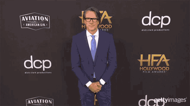 a man in a blue suit is standing in front of a wall that says dcp on it