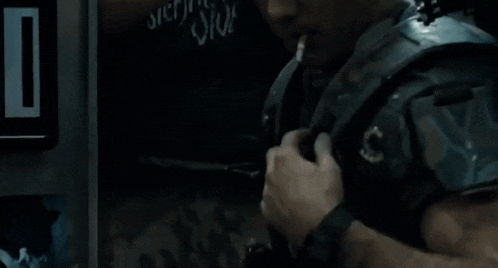a close up of a person holding a gun in a dark room in a movie .