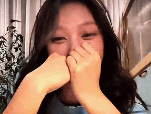 a close up of a woman covering her mouth with her hands with a watermark that says njsfuerie