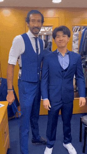 a man in a blue suit is standing next to another man in a white shirt