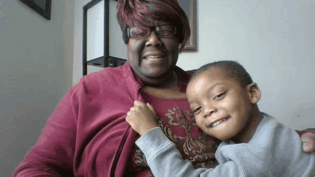 a woman in a red jacket is holding a little boy