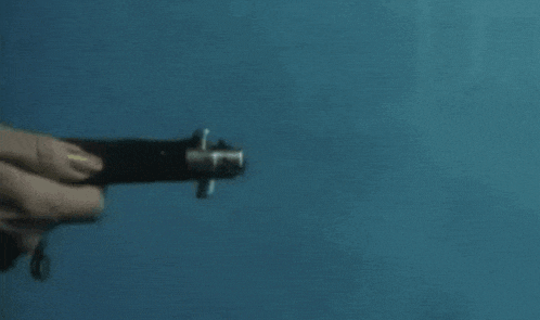 a person is holding a flashlight in their hand against a blue wall .