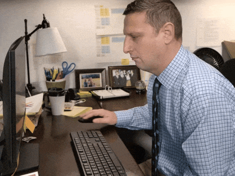 a man sits at a desk using a computer keyboard