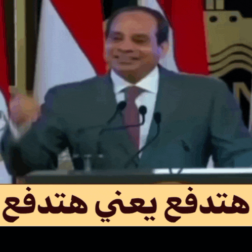 a man in a suit and tie is giving a speech in front of two microphones