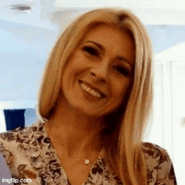 a woman with blonde hair and a floral shirt is smiling .