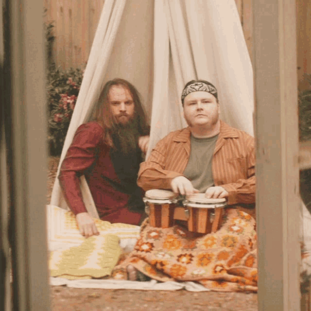 a man with a bandana on his head sits next to another man