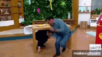 two men are kneeling under a table with a cartoon mineira logo on the bottom