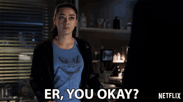 a woman wearing a blue shirt with a cat on it says er you okay