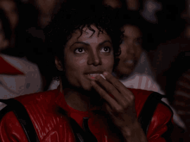 a man in a red jacket is eating popcorn in front of a crowd