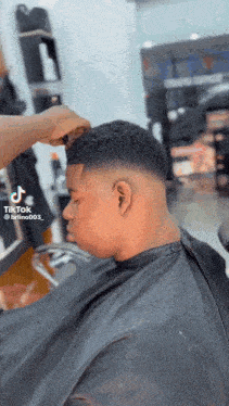 a young man is getting his hair cut by a barber in a barber shop .