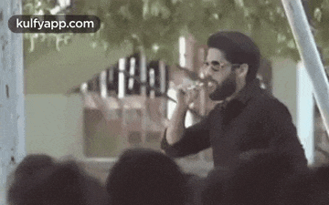 a man is singing into a microphone in front of a crowd .