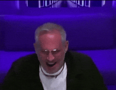 a man in a black jacket and white shirt is dancing in front of a purple background