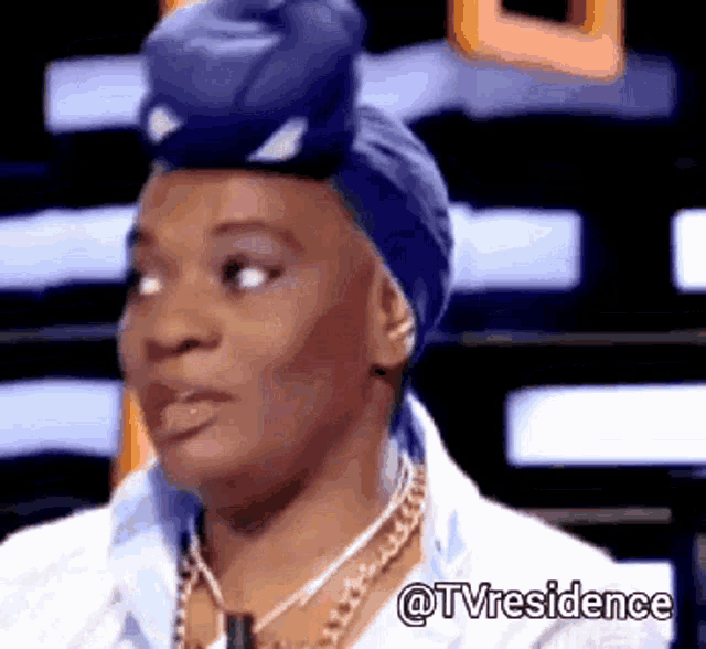 a woman wearing a blue turban and a necklace with the words @tvresidence written below her