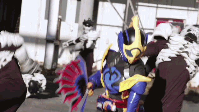 a man in a blue and yellow costume is fighting a group of people .
