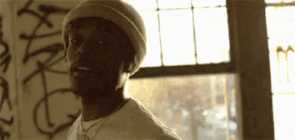 a man in a hat is standing in front of a window .