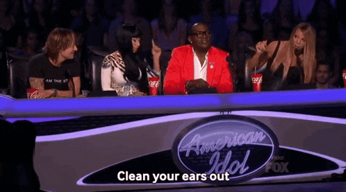 a group of people sitting in front of a sign that says " clean your ears out "