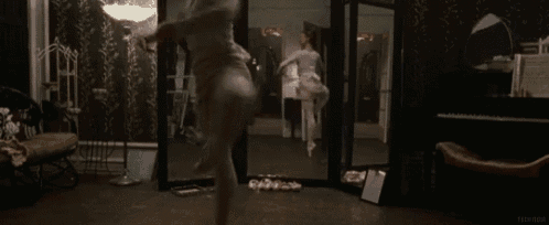 a woman is dancing in front of a mirror in a room with a piano .