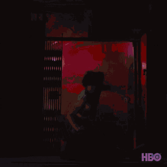 a shirtless man is dancing in a dark room with purple lights behind him .
