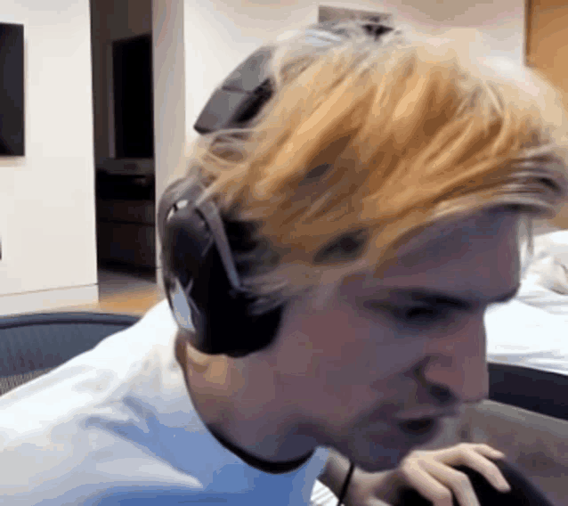 a man with blonde hair is wearing headphones and looking at something