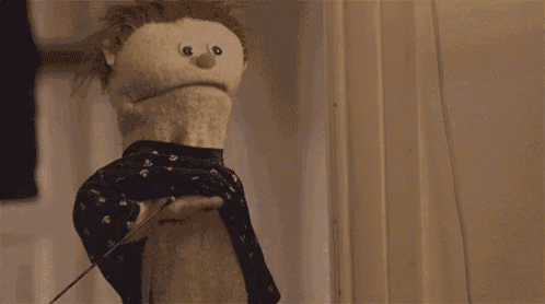 a puppet is wearing a black dress and standing next to a window .