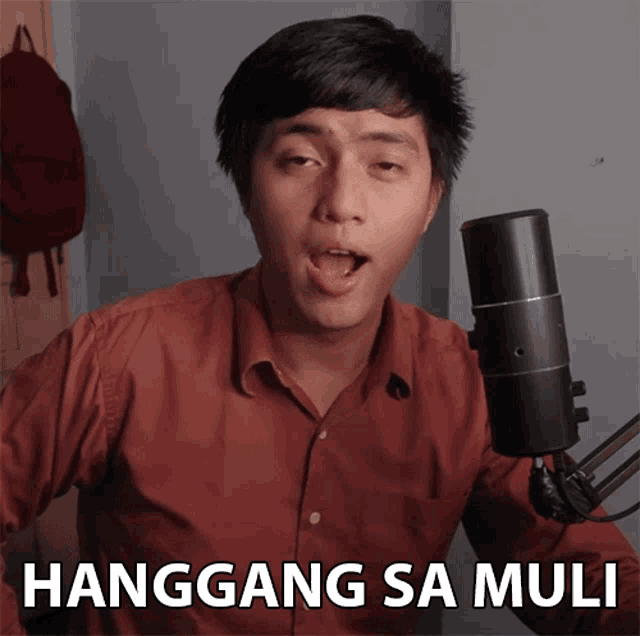 a man singing into a microphone with the words " hanggang sa muli " behind him