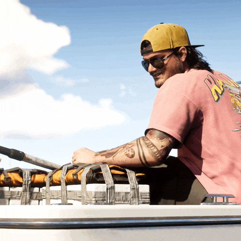 a man wearing a pink shirt that says ' nz ' on the back sits on a boat